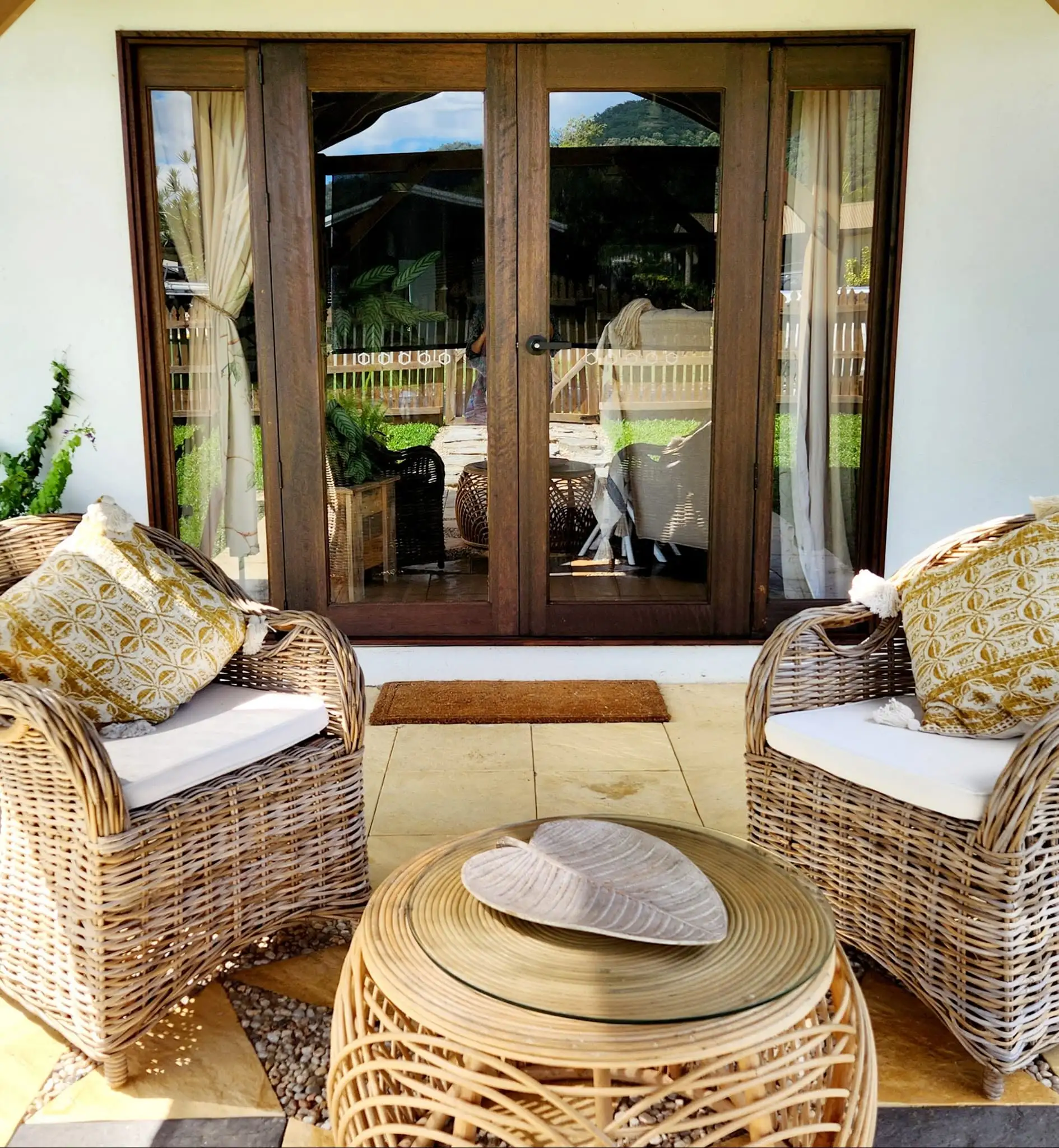 Outdoor lounge setting on a paved patio beside timber French doors