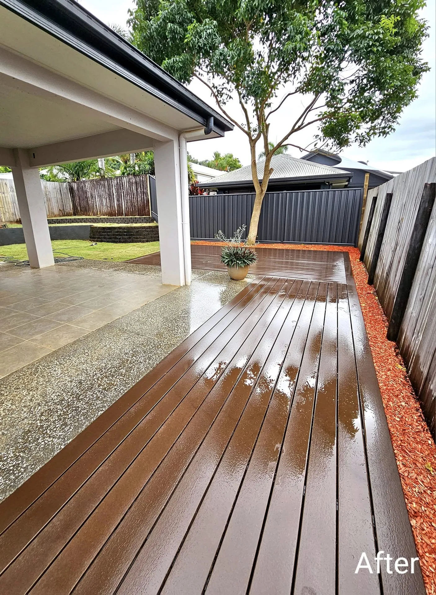 Completed timber deck beside a home with an established tree and boundary fencing