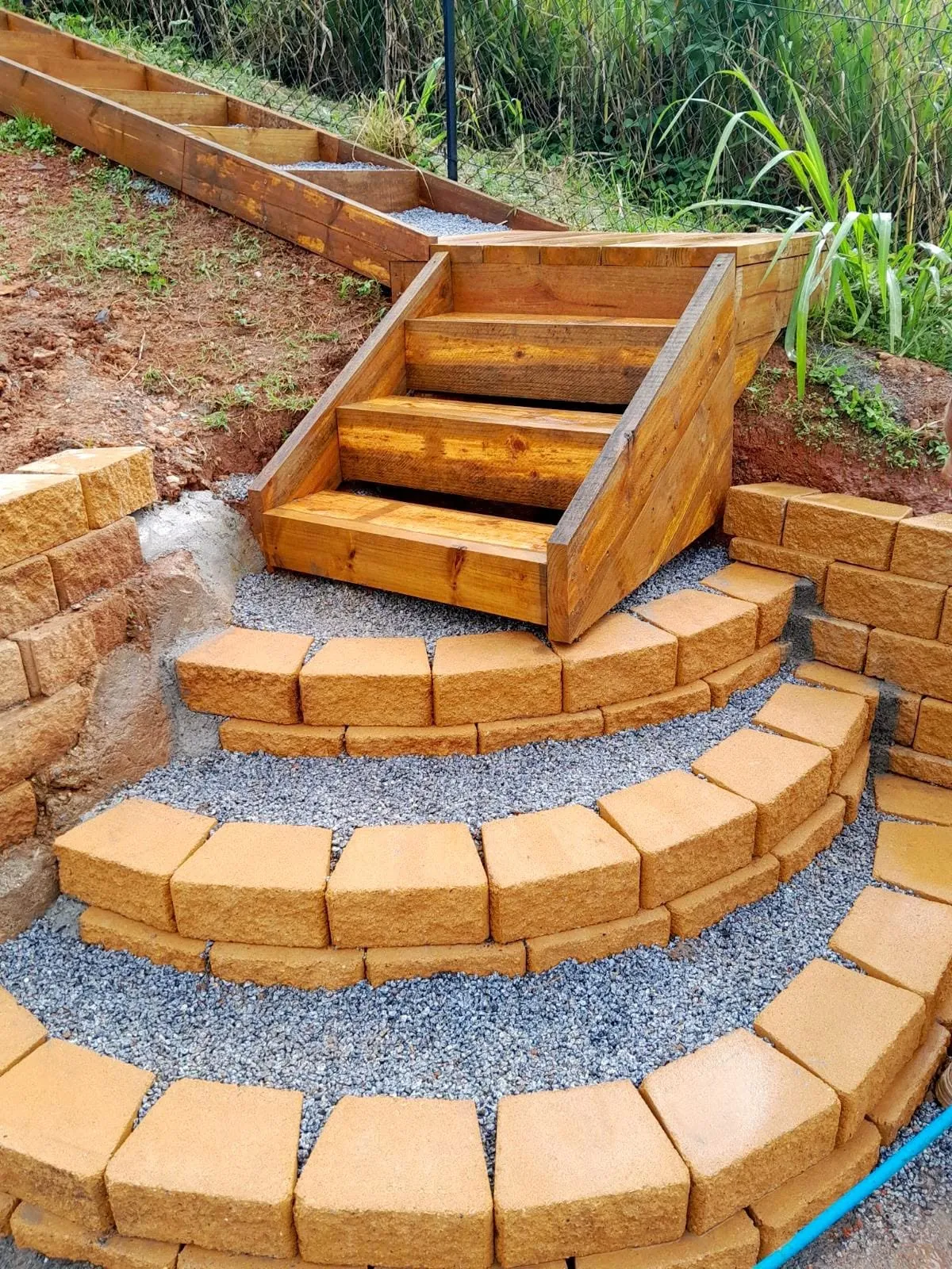 Curved sandstone block steps linking a timber deck down to a landscaped garden
