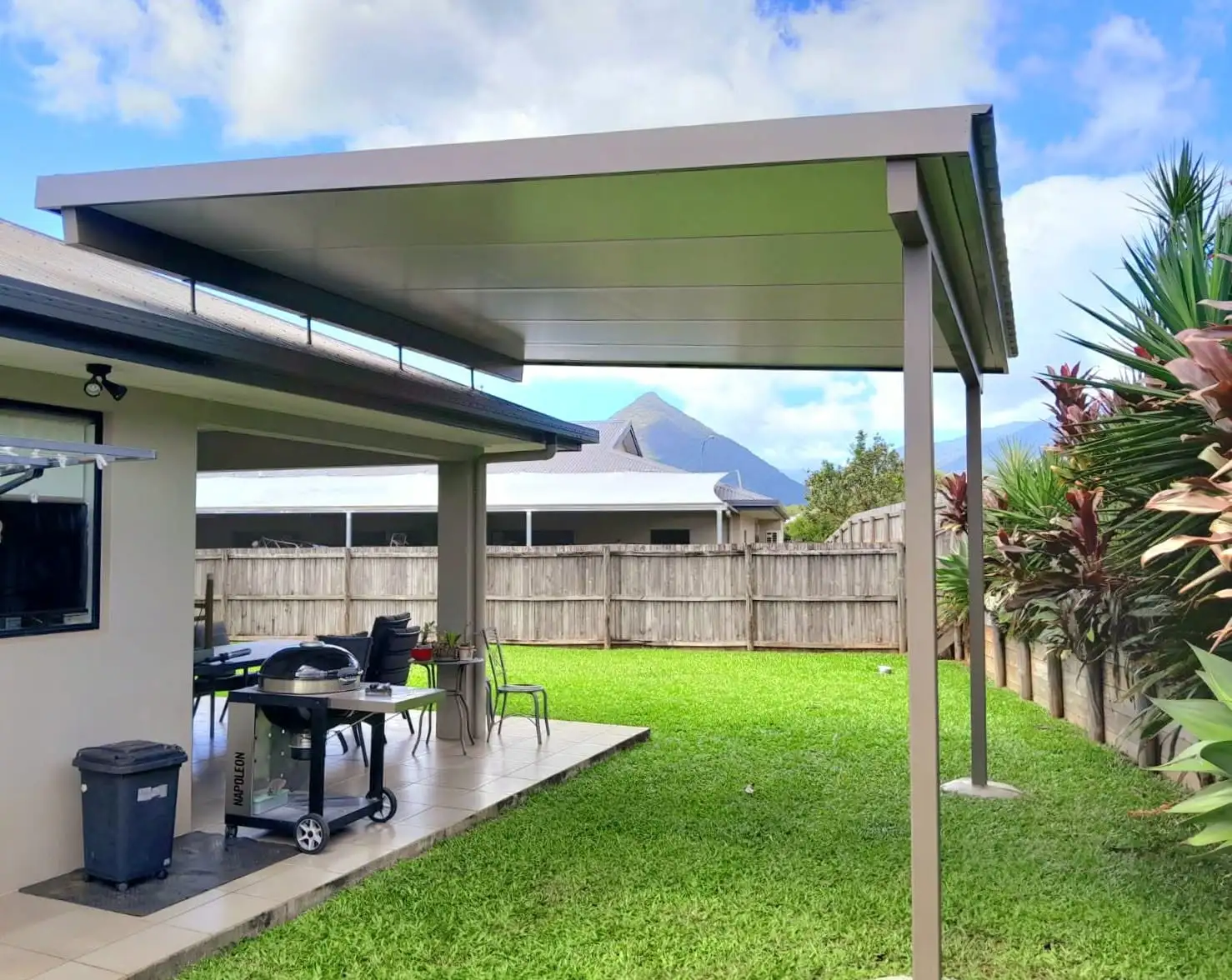 Patio cover over a paved outdoor living area with lawn and mountain views
