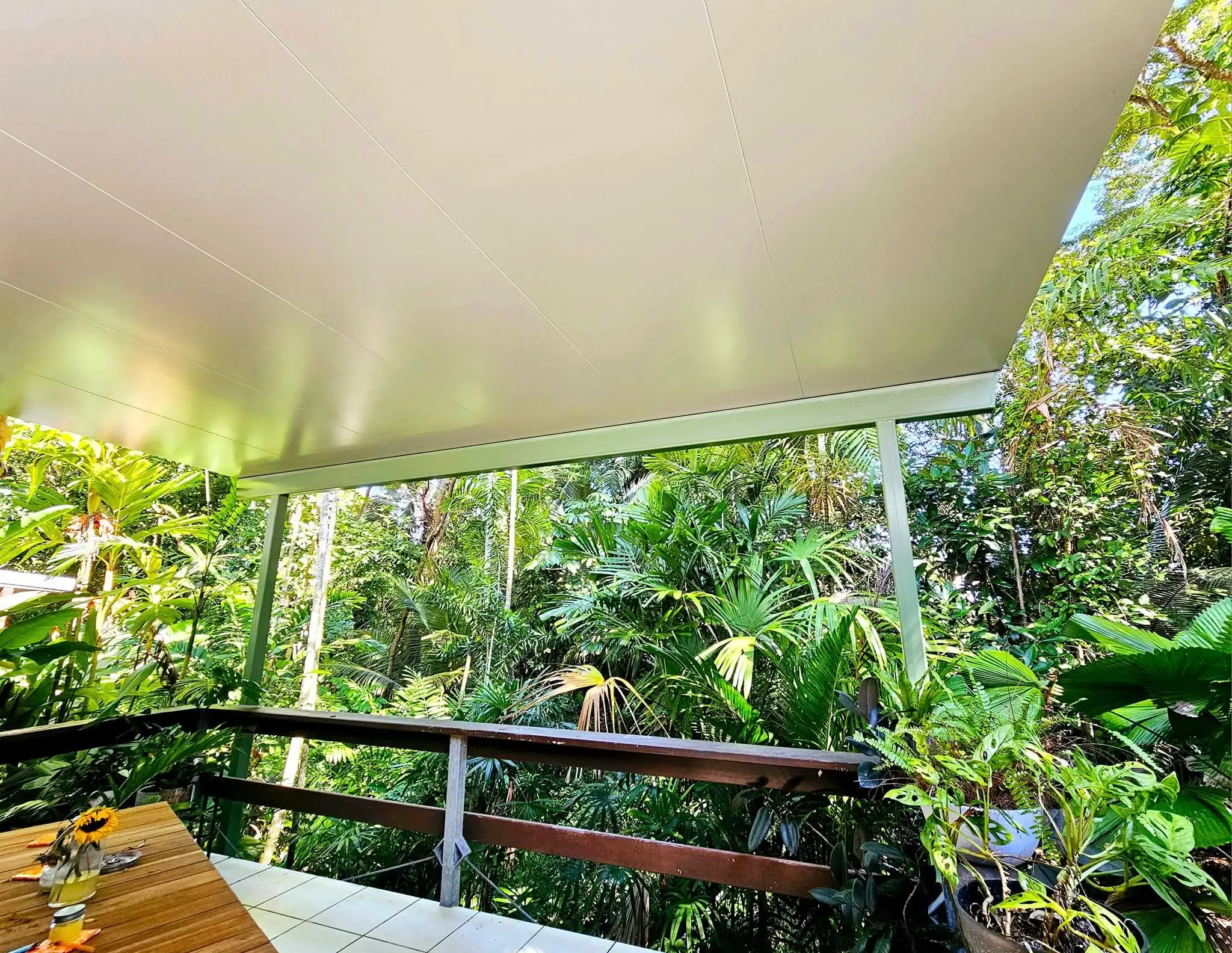 View from a covered timber deck out to rainforest through a timber balustrade