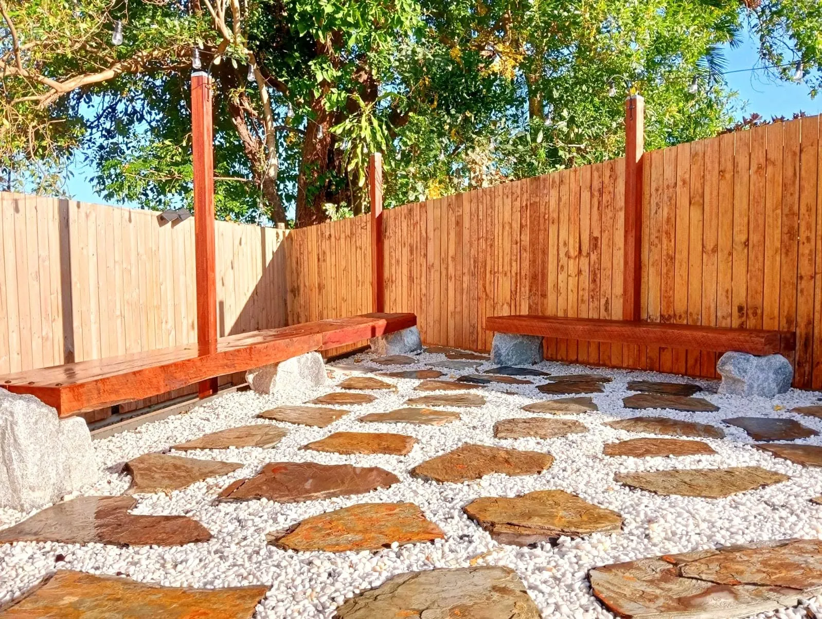 Custom stone paving set in white gravel beside a timber fence and built-in bench seat