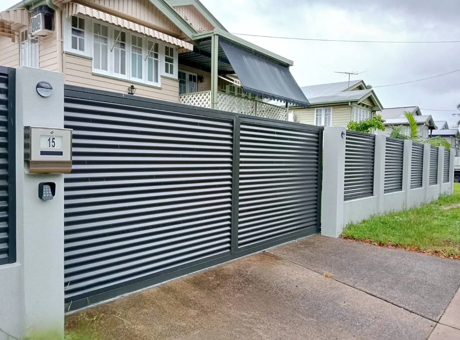 Automatic slat driveway gate and matching fence at a home entrance