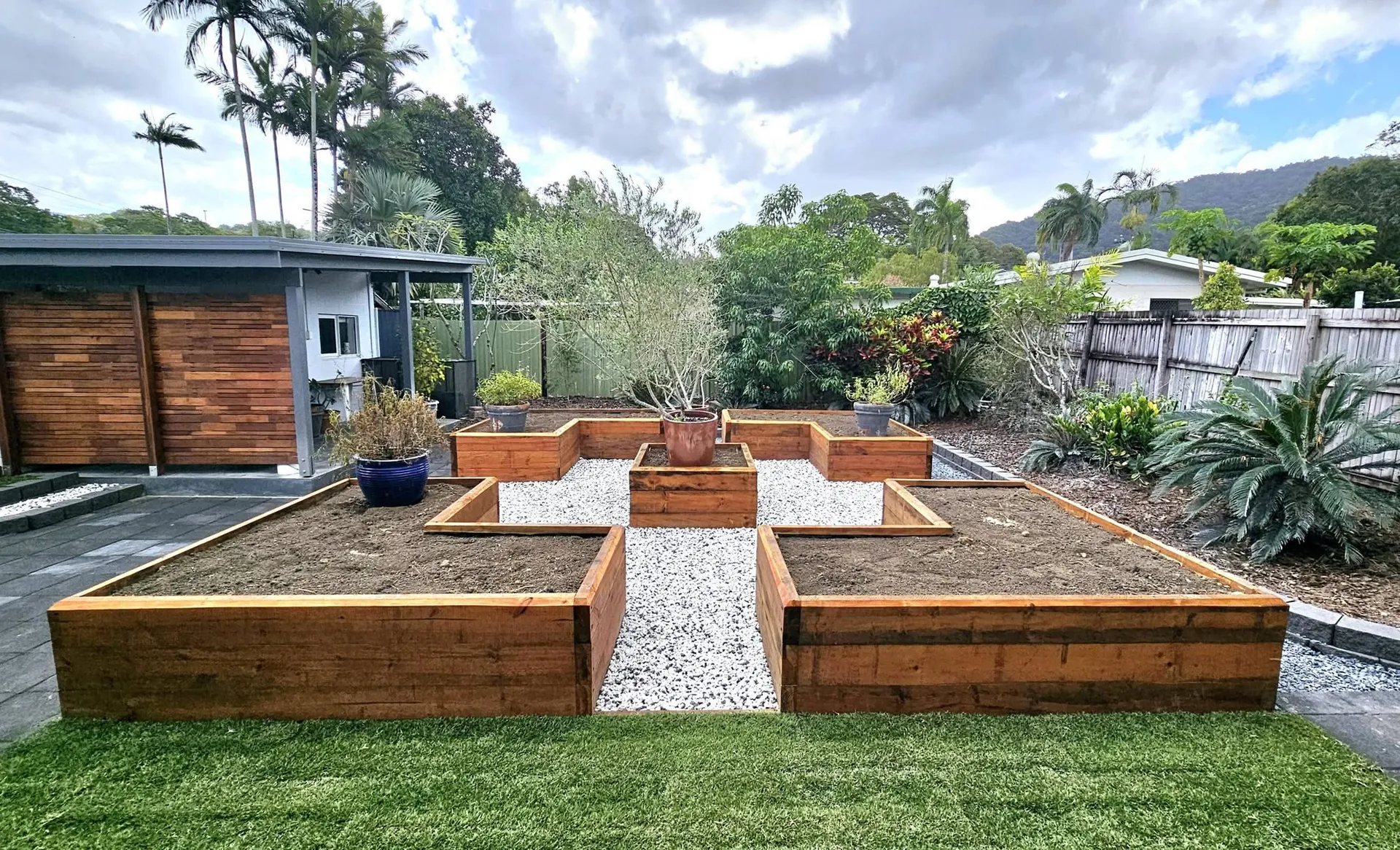 Raised timber garden beds with gravel paths in a landscaped backyard