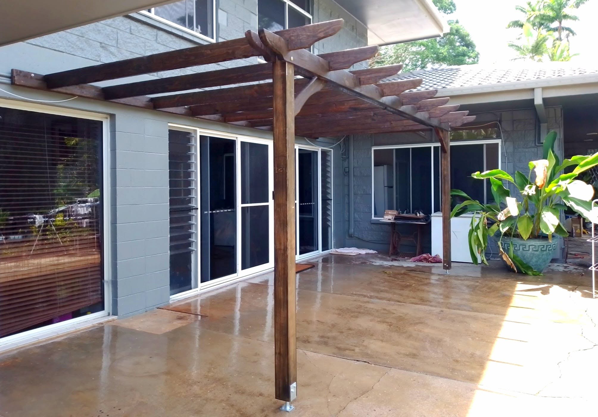 Timber pergola built over a concrete courtyard against a home